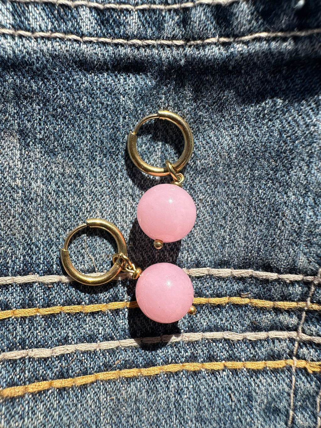 Pair of pink beaded earrings with gold loops and hoops on a denim background