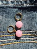 Pair of pink beaded earrings with gold loops and hoops on a denim background
